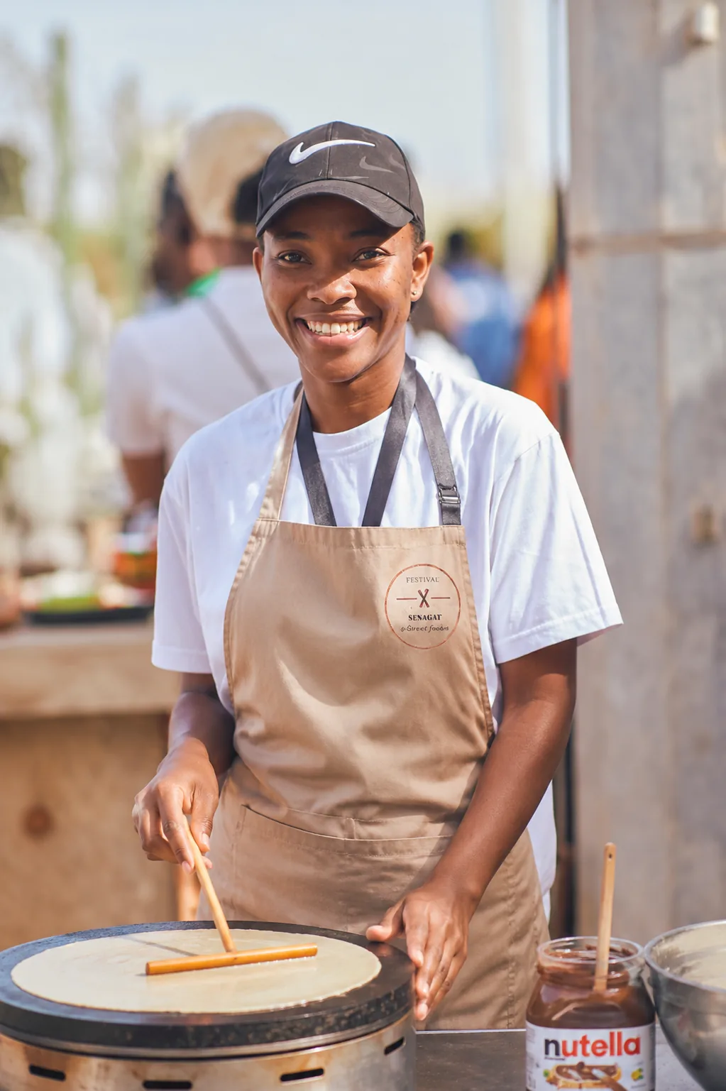 Béniafet Diane, fondatrice, étalant une pâte à crêpe sur la crêpière lors d'un festival street food à Dakar